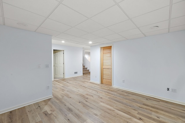 spare room featuring a paneled ceiling and light hardwood / wood-style floors