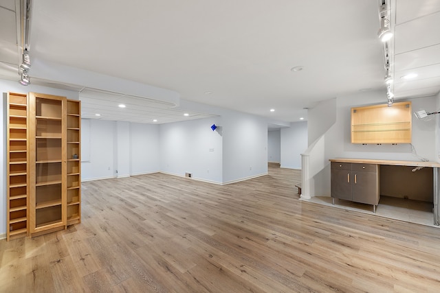 unfurnished living room featuring track lighting and light wood-type flooring