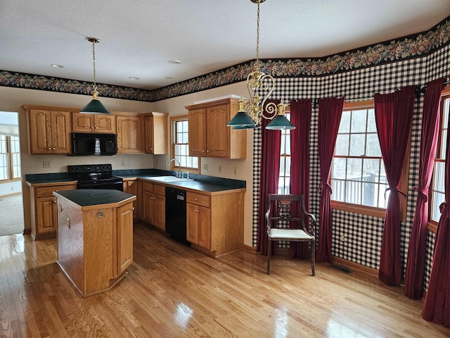 kitchen with sink, light hardwood / wood-style flooring, hanging light fixtures, a center island, and black appliances