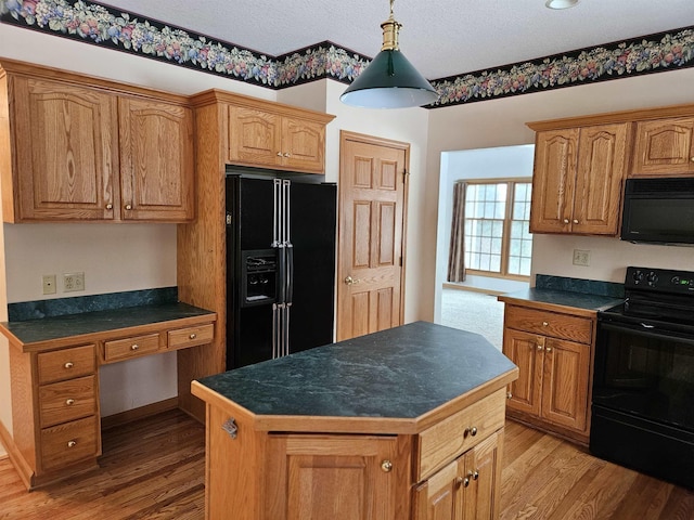 kitchen featuring wood-type flooring, built in desk, a kitchen island, and black appliances