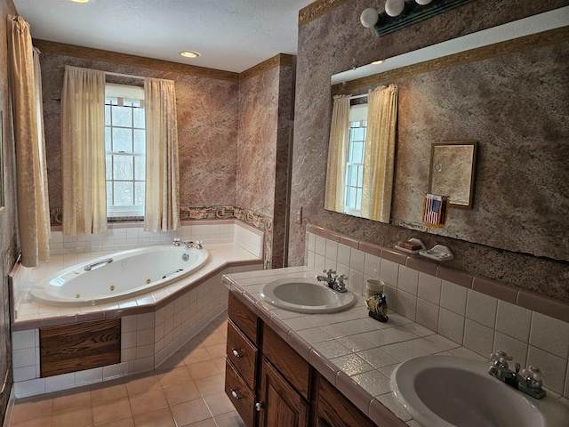 bathroom with tile patterned floors, a textured ceiling, vanity, and tiled tub