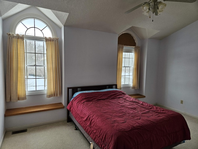 carpeted bedroom with multiple windows, ceiling fan, vaulted ceiling, and a textured ceiling