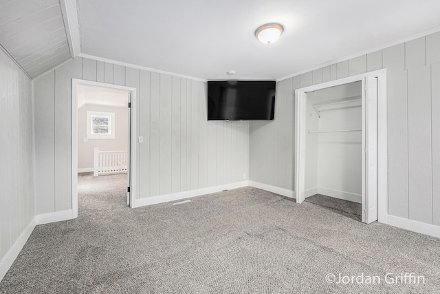 unfurnished bedroom featuring vaulted ceiling, carpet floors, and a closet