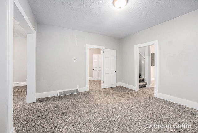 carpeted spare room featuring a textured ceiling