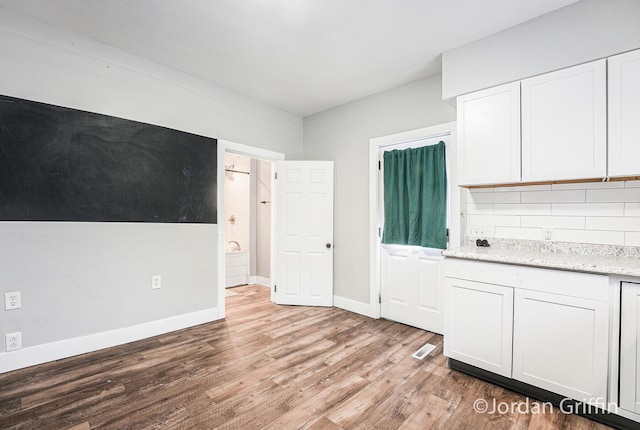 kitchen featuring white cabinetry, light stone countertops, tasteful backsplash, and light hardwood / wood-style floors