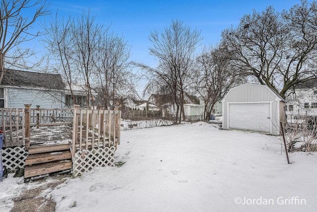 yard covered in snow featuring an outbuilding, a garage, and a deck