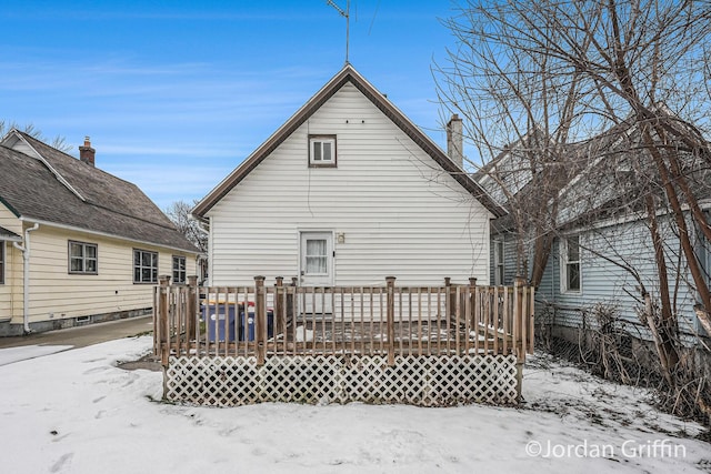 snow covered rear of property with a deck