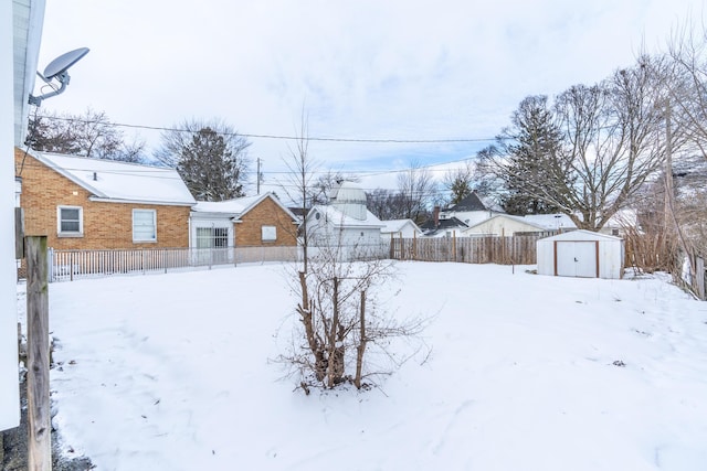 snowy yard featuring a storage unit