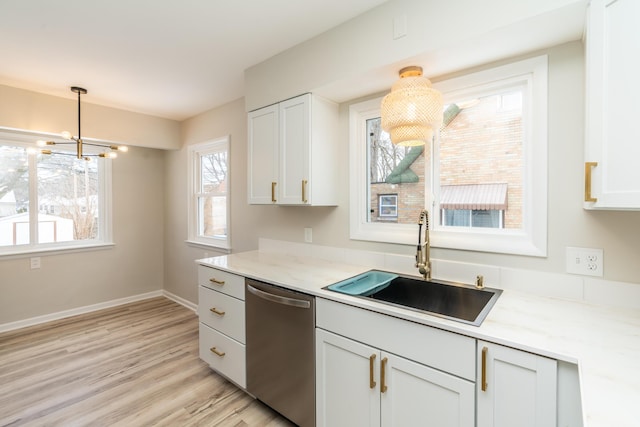 kitchen featuring hanging light fixtures, dishwasher, sink, and light stone counters