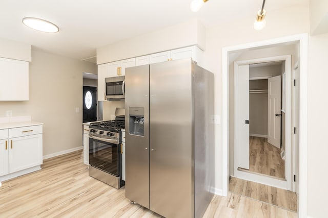 kitchen with appliances with stainless steel finishes, light wood-type flooring, and white cabinets