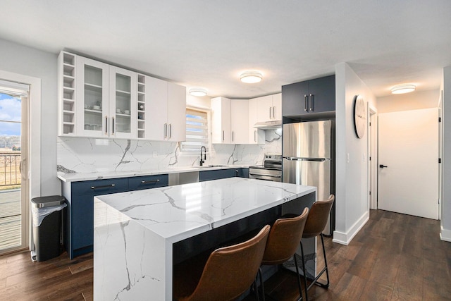 kitchen featuring appliances with stainless steel finishes, white cabinetry, sink, a center island, and blue cabinetry