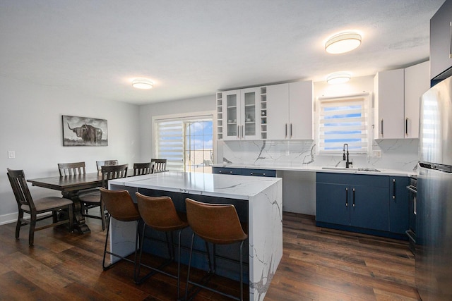 kitchen featuring blue cabinets, sink, a center island, stainless steel refrigerator, and white cabinets