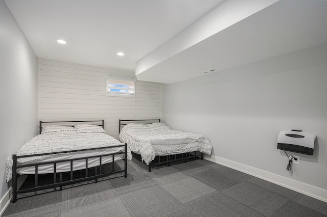 carpeted bedroom featuring heating unit and wooden walls