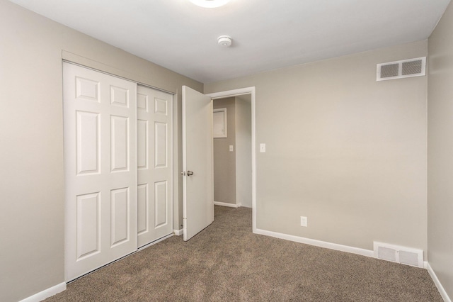 unfurnished bedroom with a closet and dark colored carpet