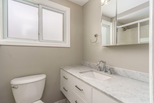 bathroom with vanity, a shower with shower door, and toilet