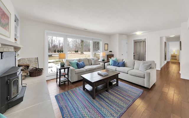 living area with dark wood-type flooring, a wood stove, and baseboards