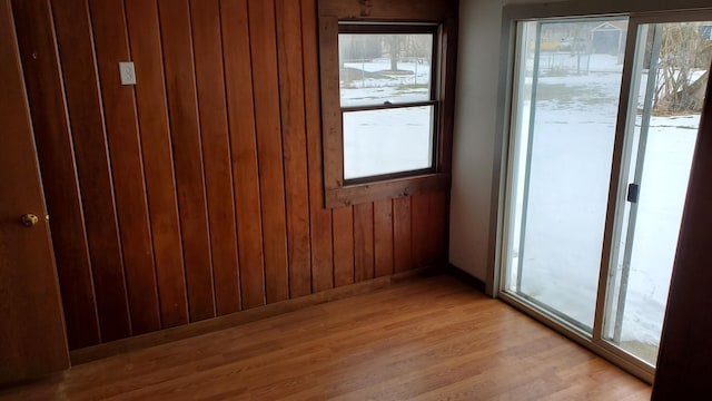 unfurnished room featuring wooden walls and light hardwood / wood-style floors