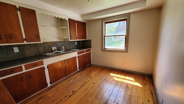 930 W Barney Ave, Muskegon, MI 49441 - kitchen with light wood-type flooring, decorative backsplash, dark countertops, open shelves, and brown cabinetry