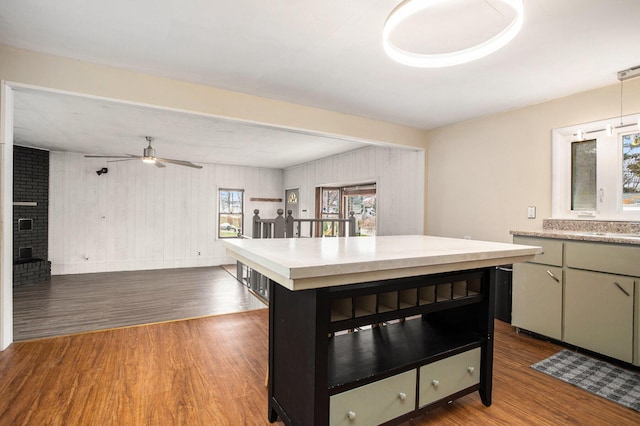 kitchen with ceiling fan, green cabinetry, wood-type flooring, and a brick fireplace