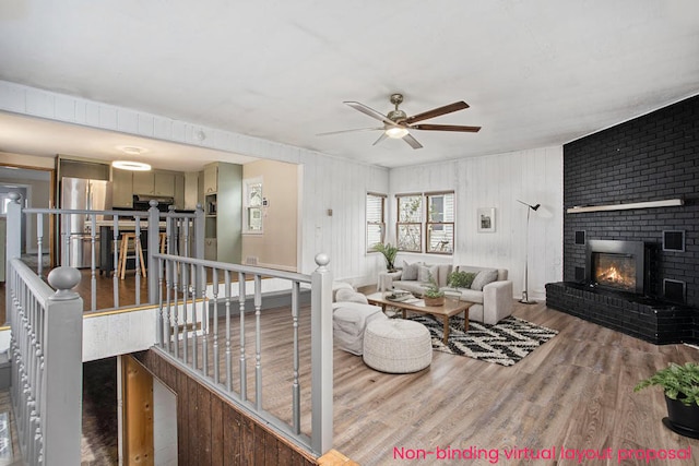 living room with wood-type flooring, ceiling fan, and a fireplace