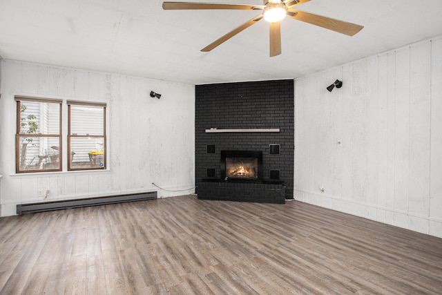 unfurnished living room featuring a baseboard radiator, hardwood / wood-style floors, ceiling fan, and a fireplace