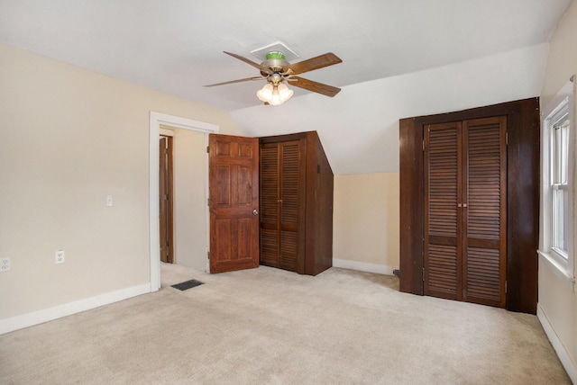 unfurnished bedroom with multiple windows, ceiling fan, lofted ceiling, and light carpet