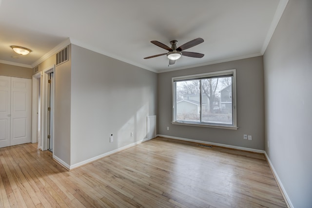 empty room with light hardwood / wood-style flooring, ornamental molding, and ceiling fan