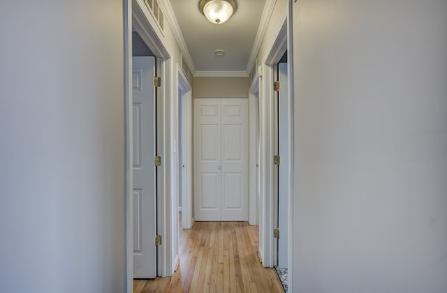 corridor featuring ornamental molding and light hardwood / wood-style flooring