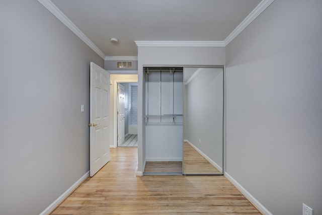 unfurnished bedroom with ornamental molding, a closet, and light hardwood / wood-style flooring