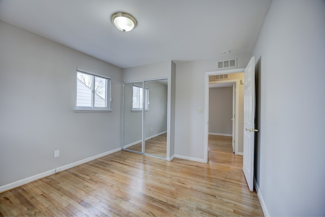 unfurnished bedroom with light wood-type flooring and a closet