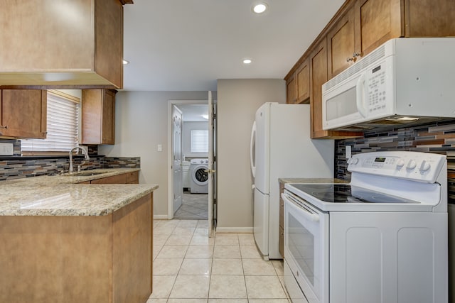 kitchen featuring sink, white appliances, light stone counters, light tile patterned flooring, and washer / dryer