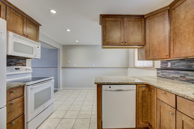 kitchen with light stone counters, light tile patterned floors, kitchen peninsula, white appliances, and backsplash