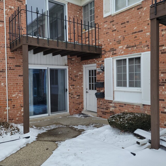 snow covered property entrance featuring a balcony