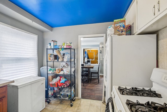 kitchen with white cabinetry, white gas range, and light tile patterned floors