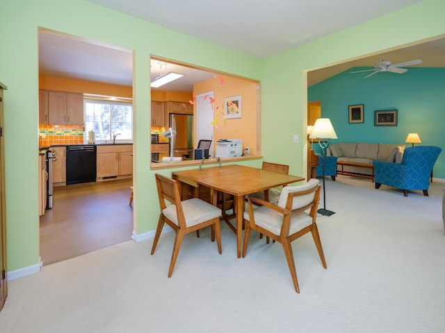 carpeted dining room featuring lofted ceiling, sink, and ceiling fan