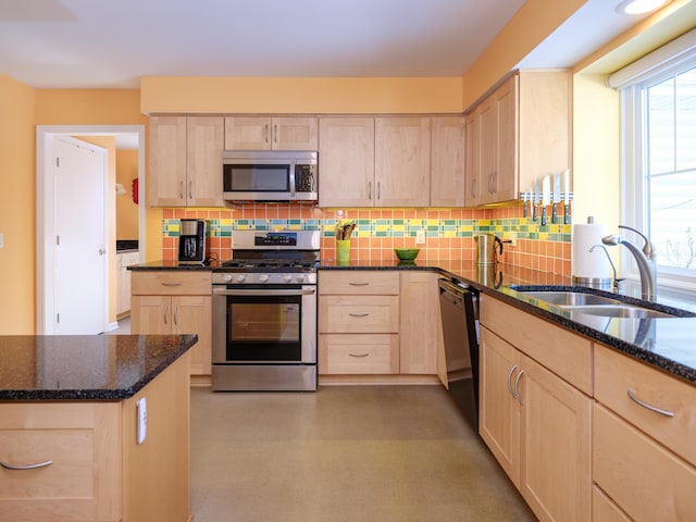 kitchen featuring stainless steel appliances, sink, dark stone counters, and light brown cabinets