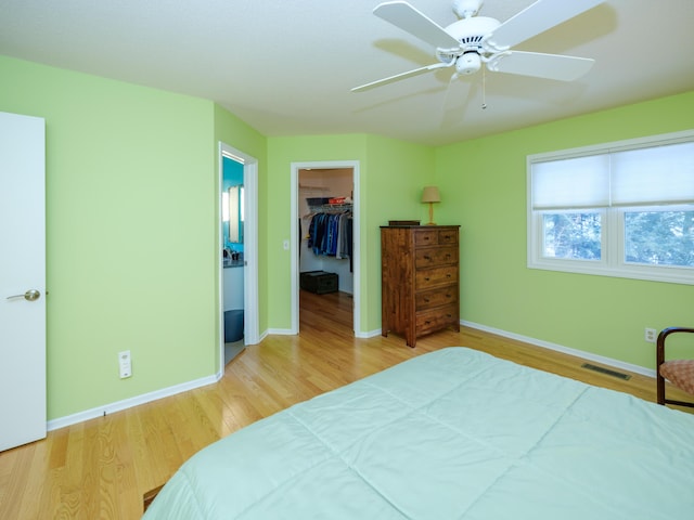 bedroom with hardwood / wood-style flooring, ceiling fan, a spacious closet, and a closet