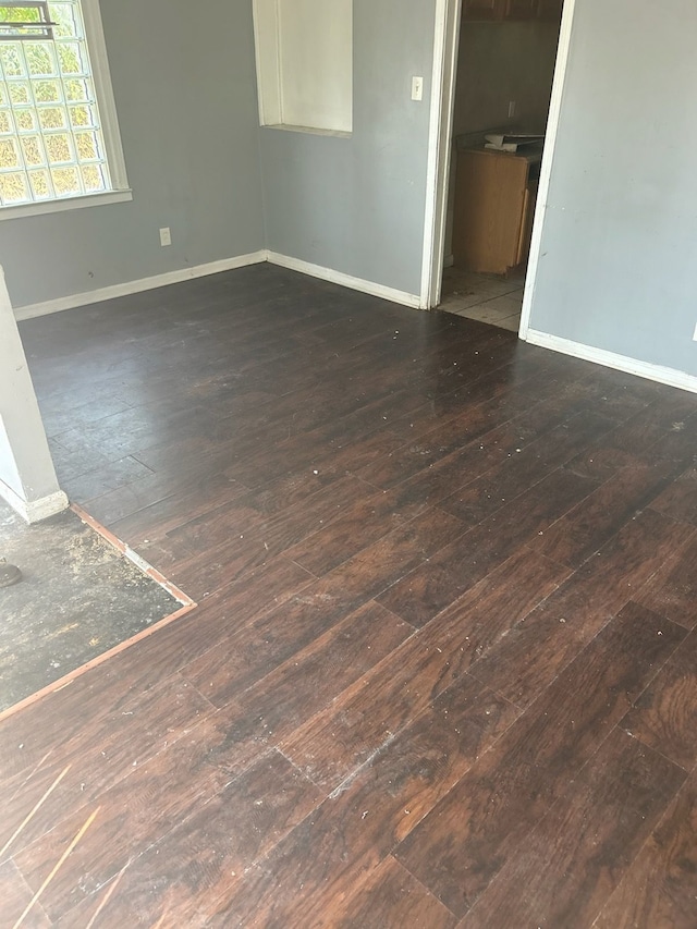 spare room with dark wood-type flooring and baseboards