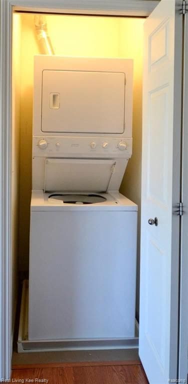 washroom with dark hardwood / wood-style floors and stacked washing maching and dryer