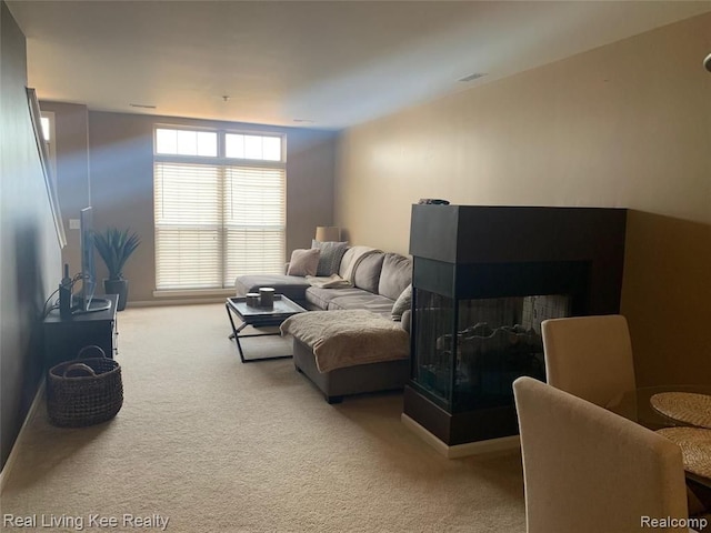 carpeted living room with a multi sided fireplace