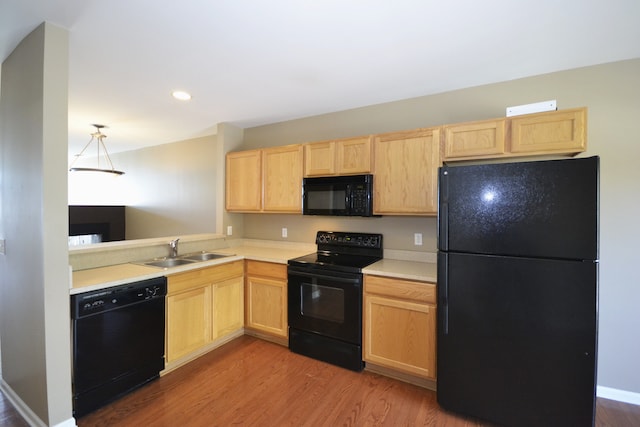 kitchen with light wood-type flooring, light brown cabinetry, sink, and black appliances