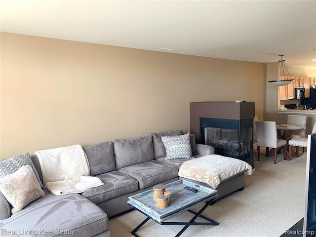 carpeted living room with a multi sided fireplace