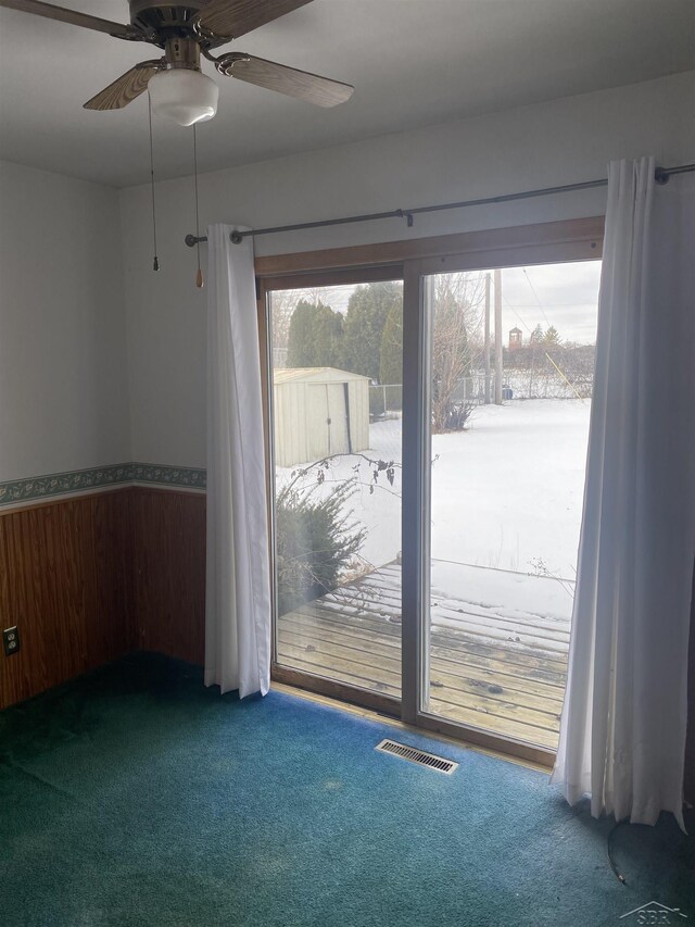 carpeted empty room featuring wooden walls and ceiling fan