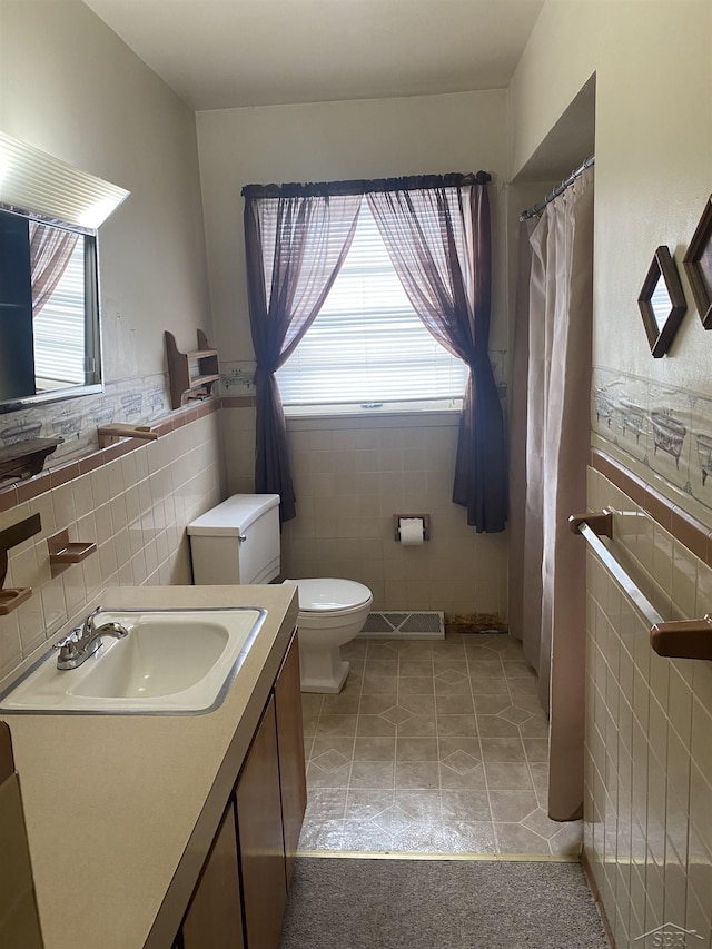 bathroom featuring vanity, a wealth of natural light, tile walls, and toilet