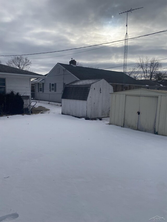 yard covered in snow featuring a storage unit