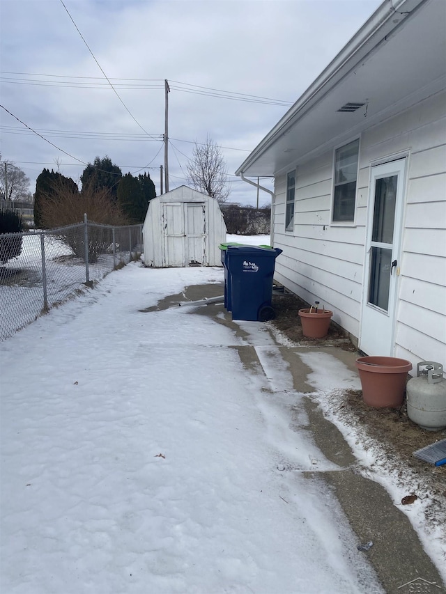 snowy yard featuring a shed