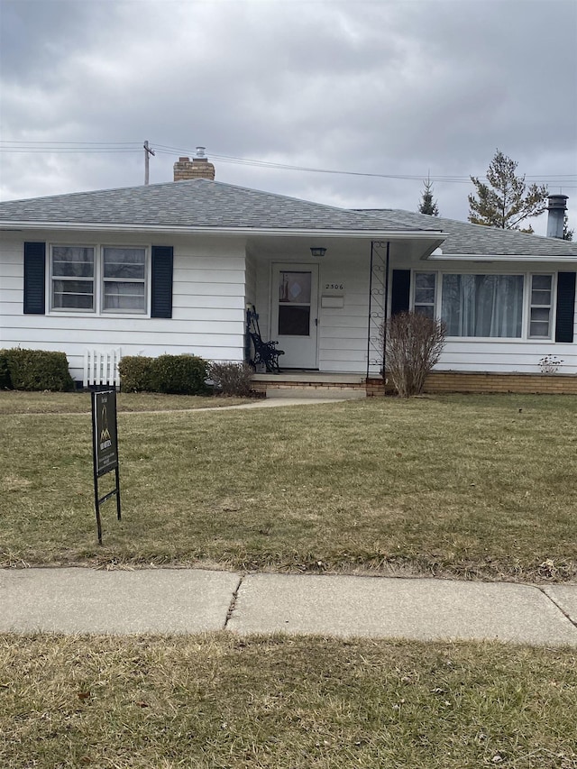 single story home featuring roof with shingles, a chimney, and a front yard