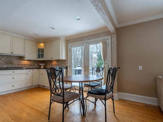 dining room with french doors, ornamental molding, light wood-style flooring, and baseboards