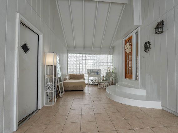 hallway with light tile patterned floors and beam ceiling