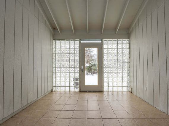 spare room featuring wood walls, beamed ceiling, and light tile patterned flooring